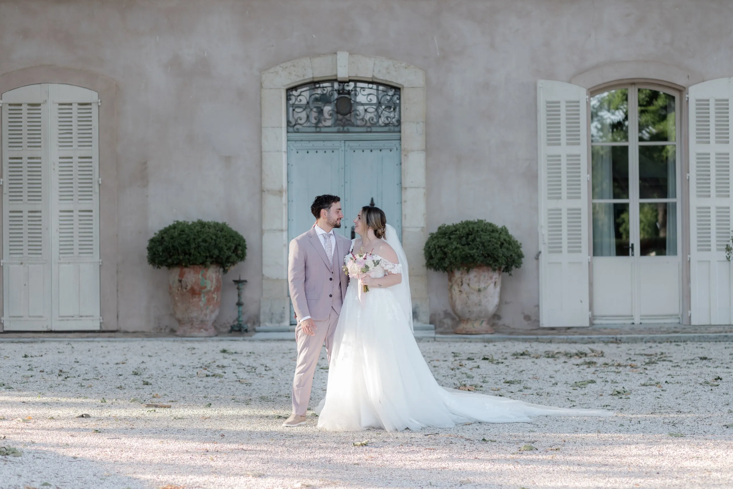 Lorena et Hugo devant la façade de la bastide, au bout de la cour de gravier