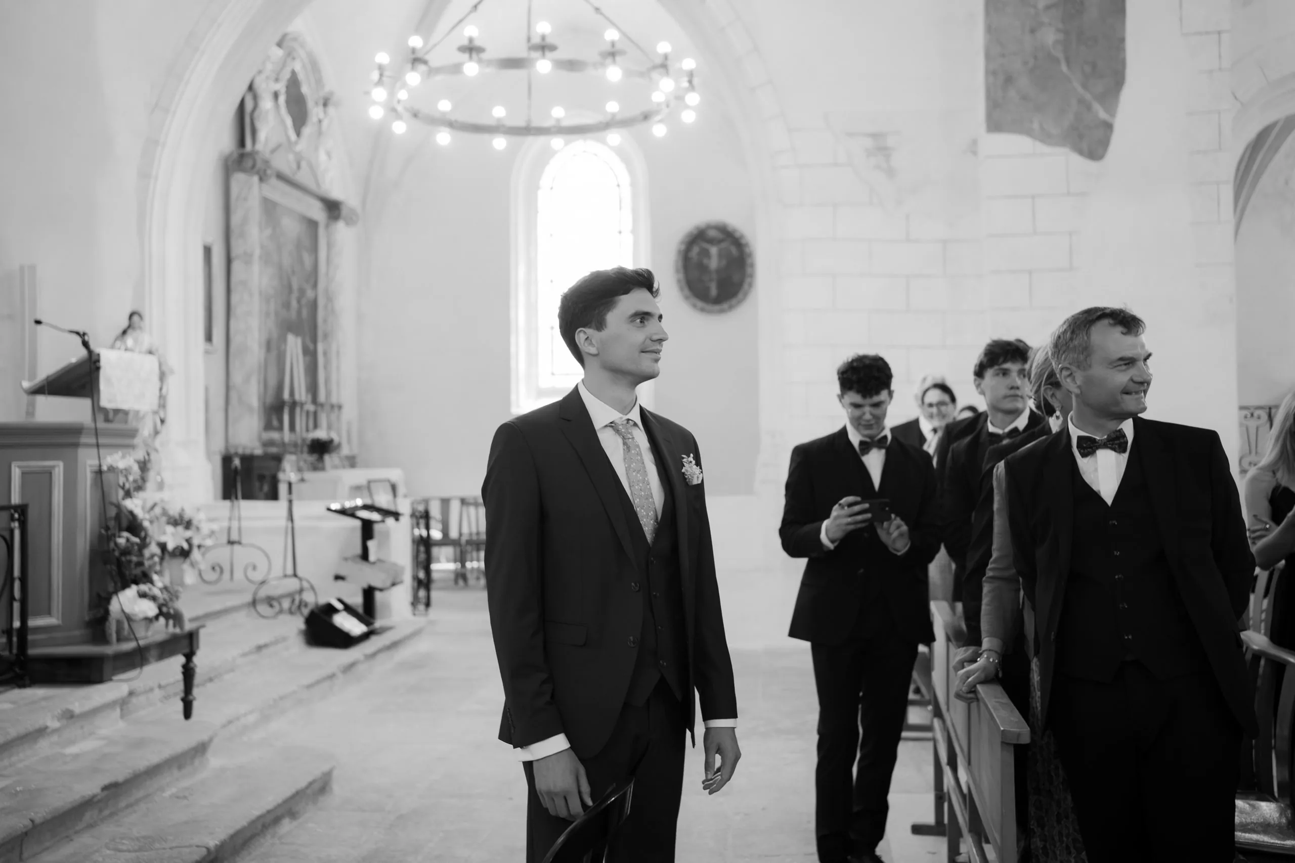 Jean attend Wieke à l'entrée de l'église, avec ses témoins, en noir et blanc
