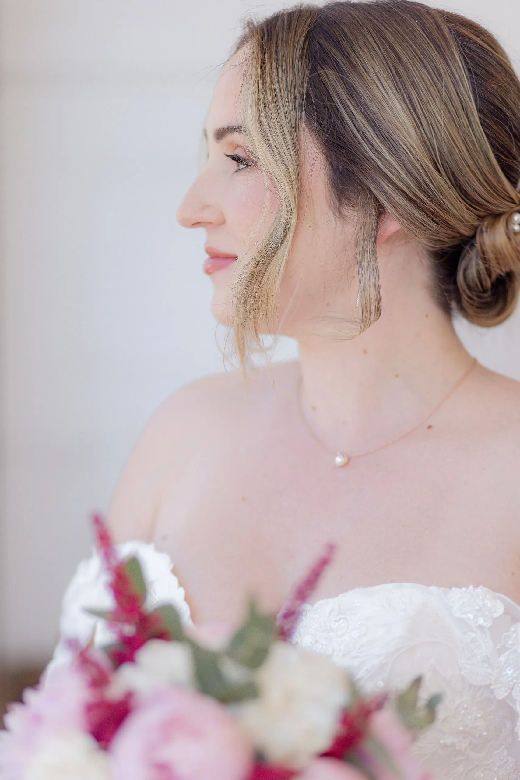 La mariée de profil, chignon bas et bouquet de pivoines