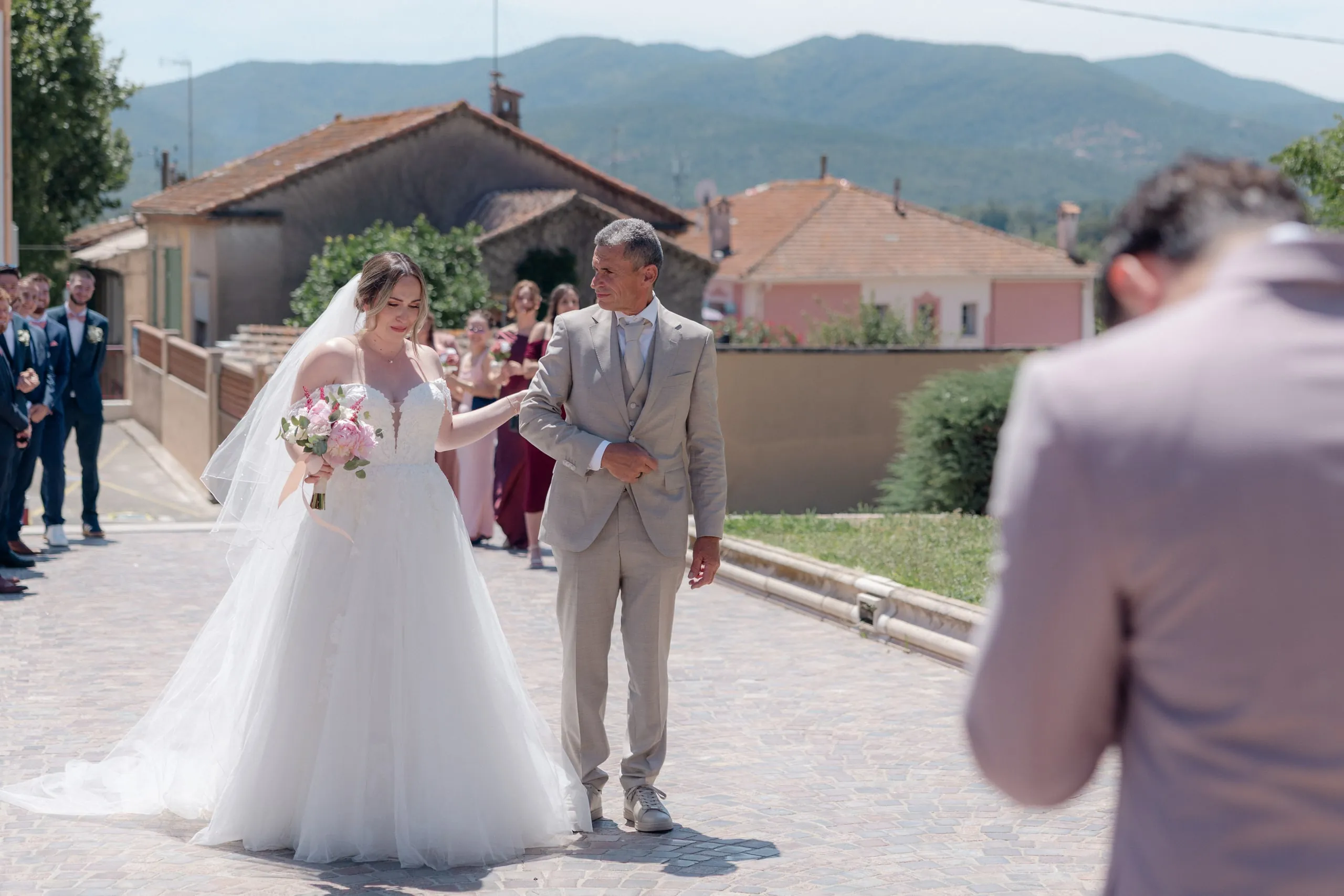 Lorena et Hugo remontent la rue du village, entourés de leurs invités