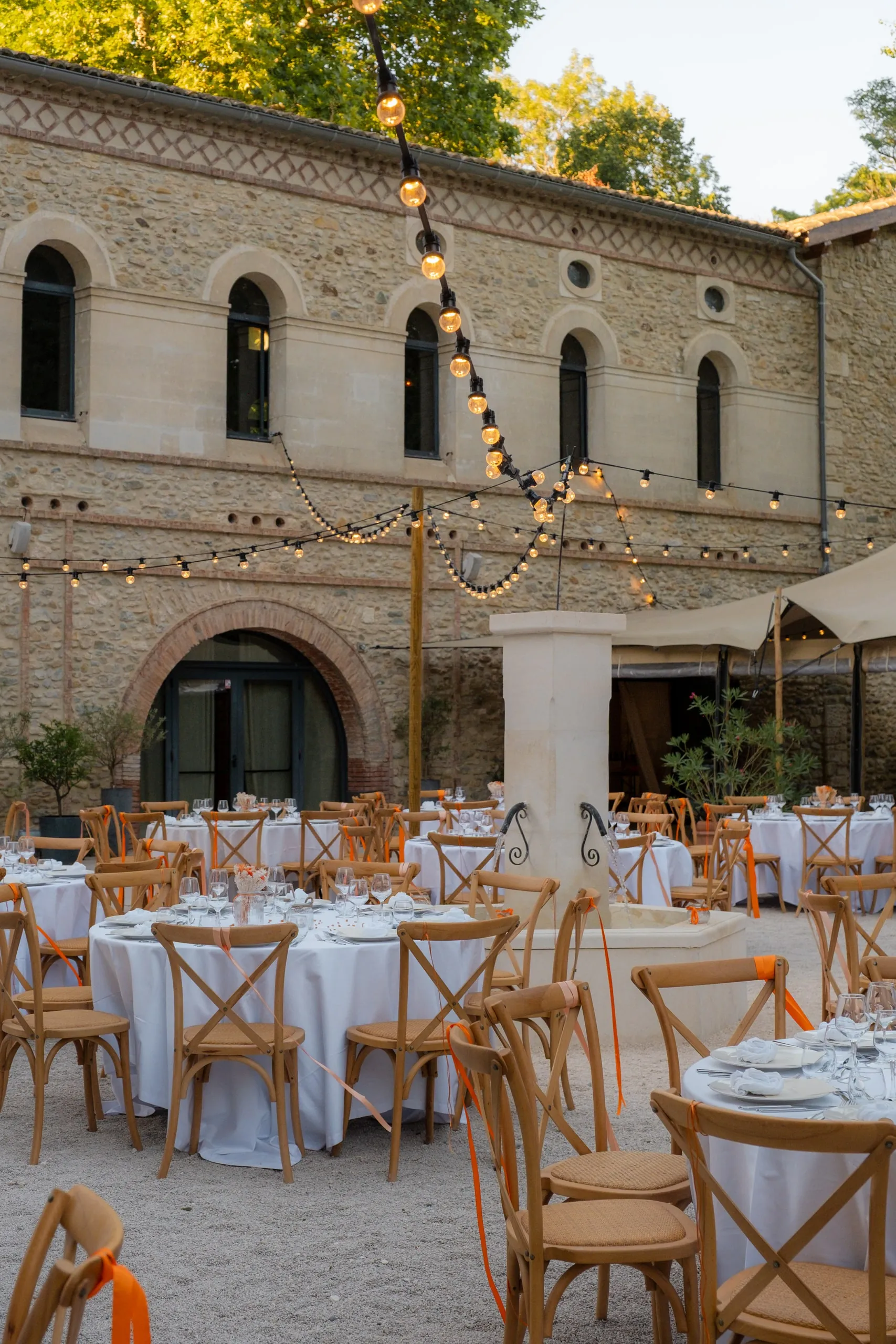 Les tables du dîner dressées sous les guirlandes, devant le bâtiment en pierre