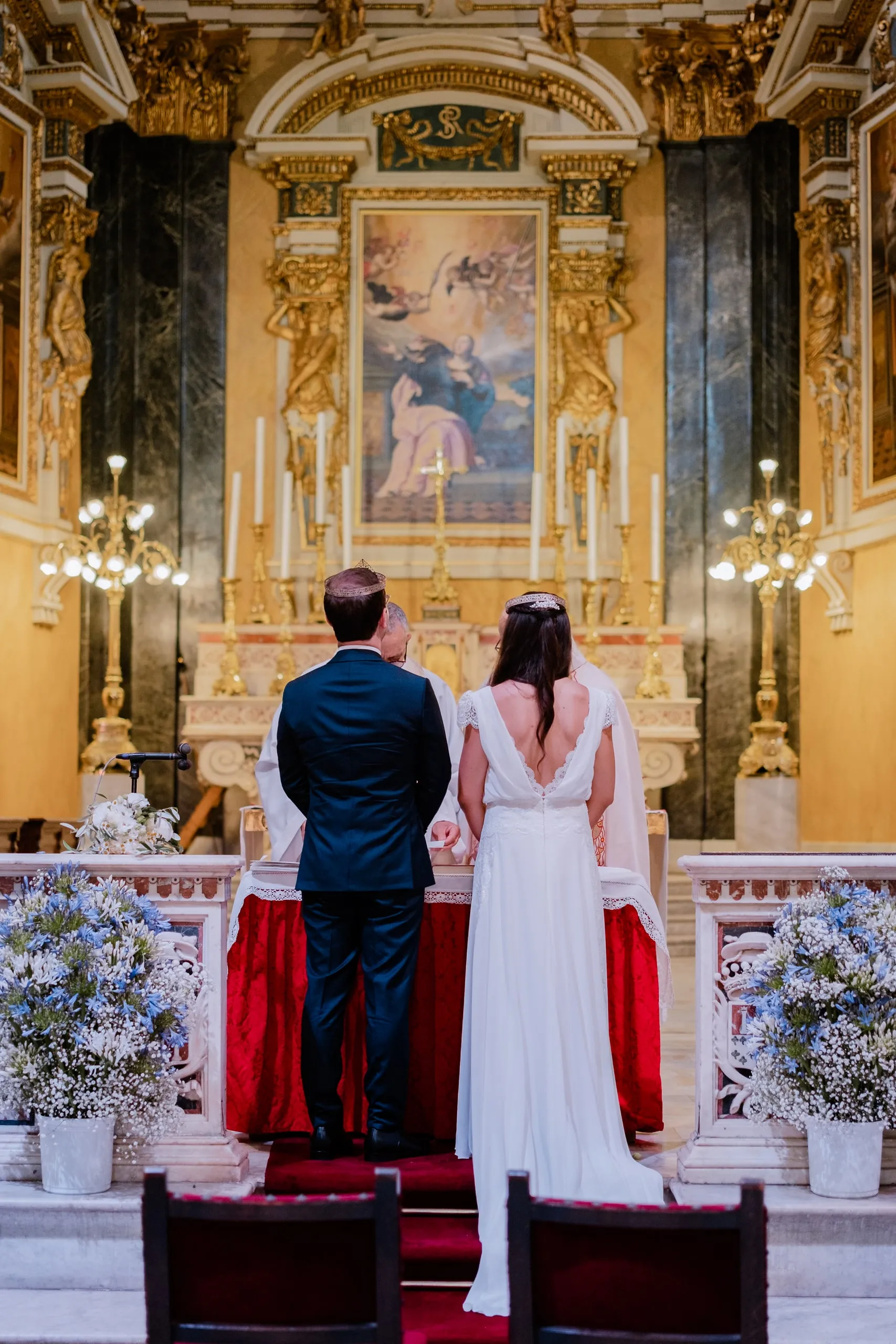 Les mariés de dos devant l'autel doré d'une église baroque