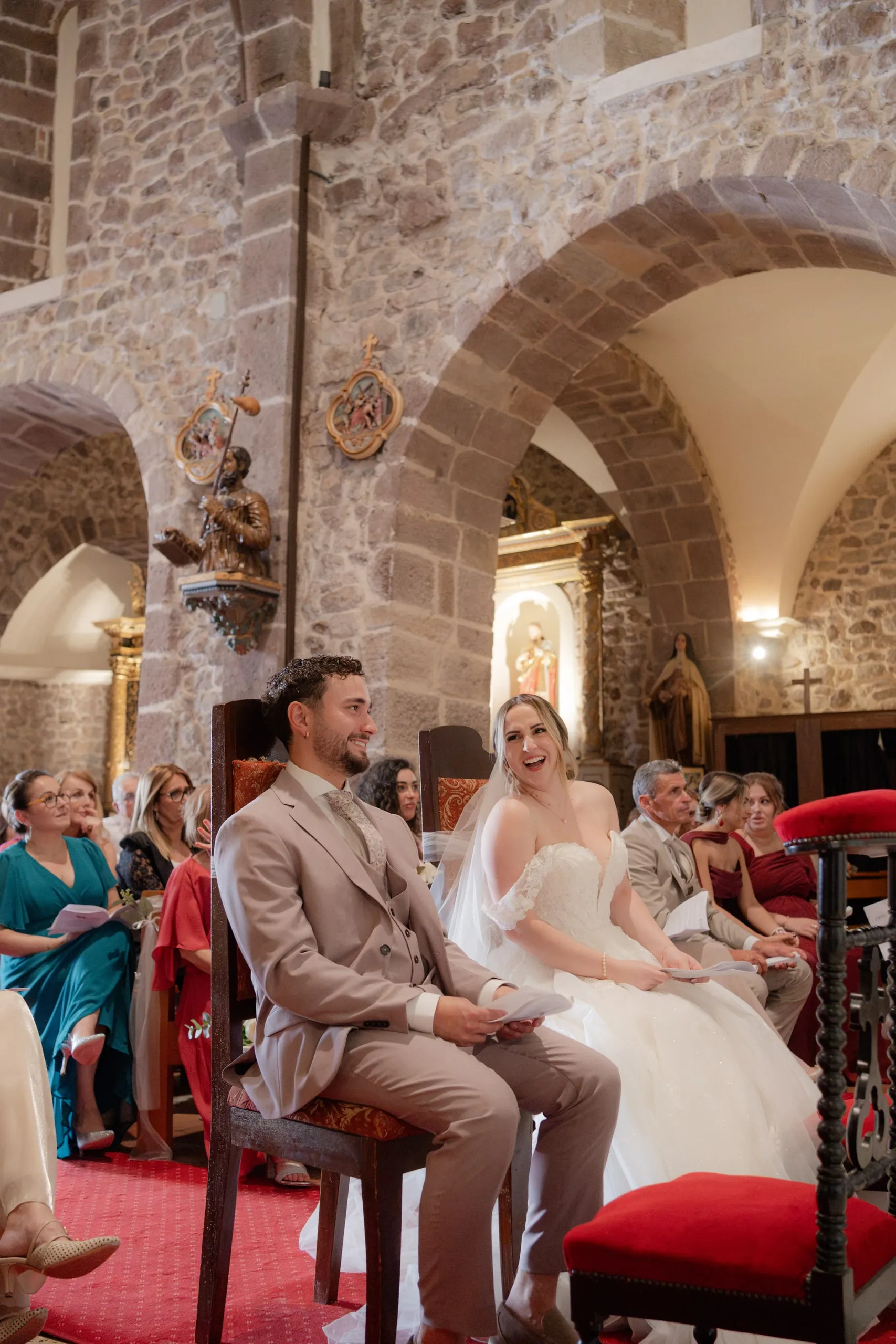 Lorena et Hugo assis devant leurs proches, dans l'église en pierre