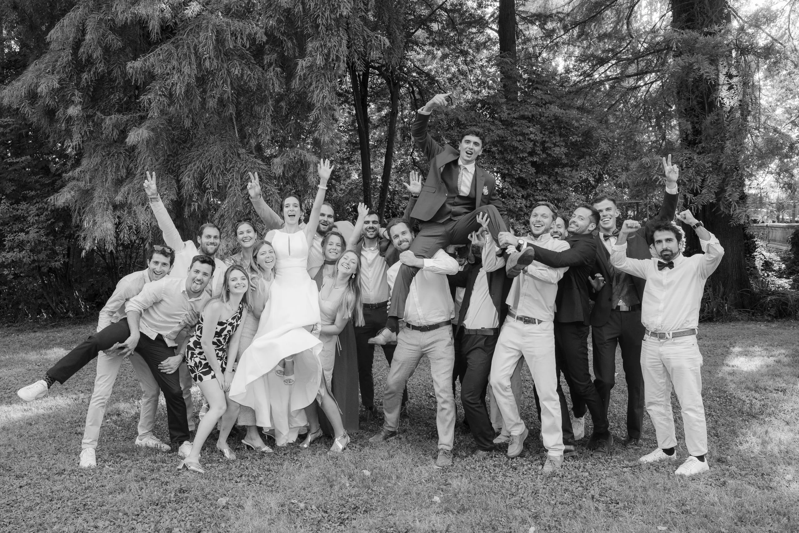 La photo de groupe de tous les invités, bras en l'air, en noir et blanc