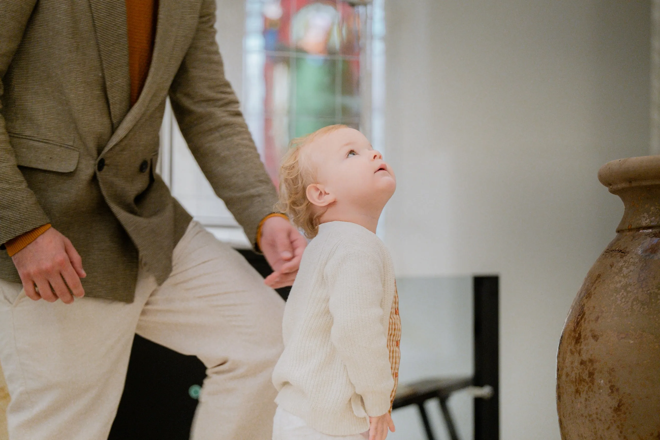 Le petit garçon lève les yeux vers son père, la main dans la sienne