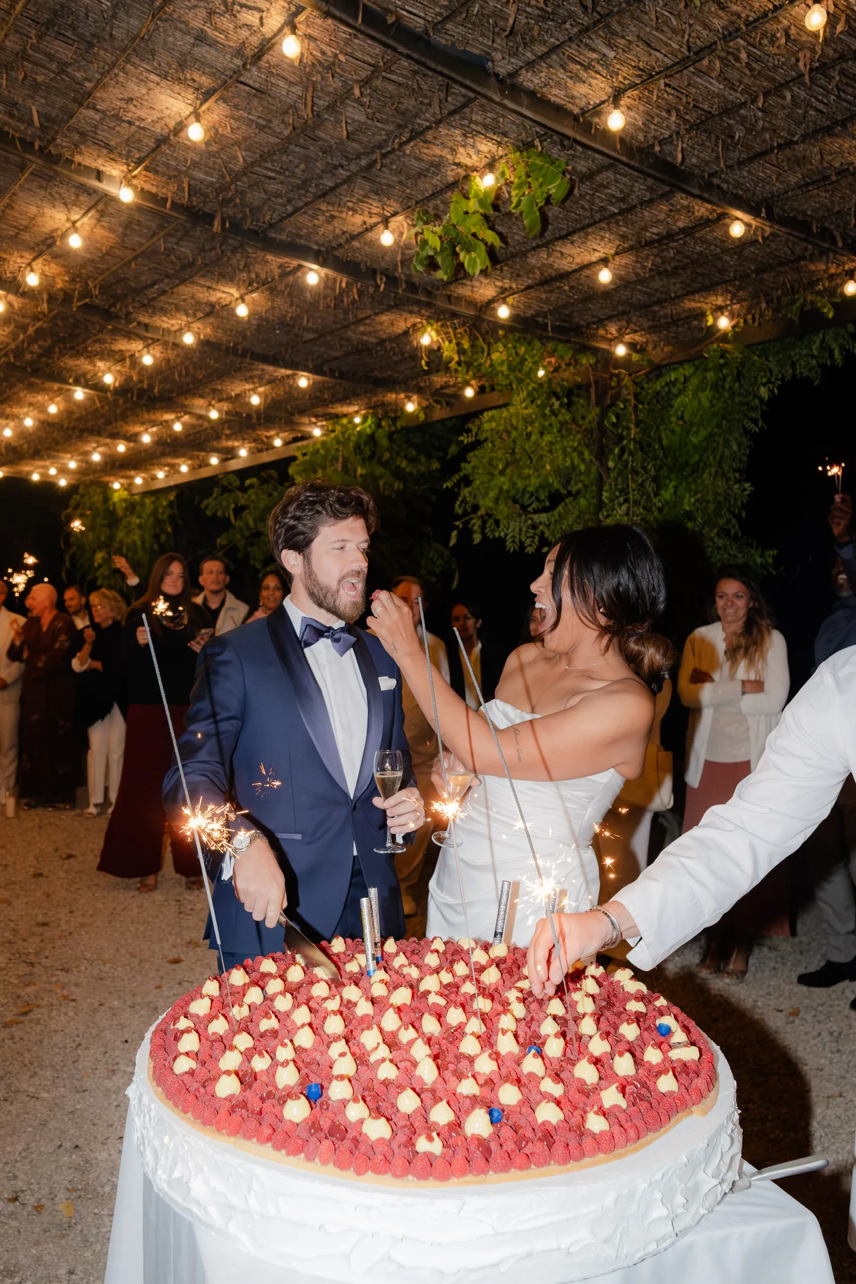 Les mariés découpent leur gâteau aux fraises sous les guirlandes