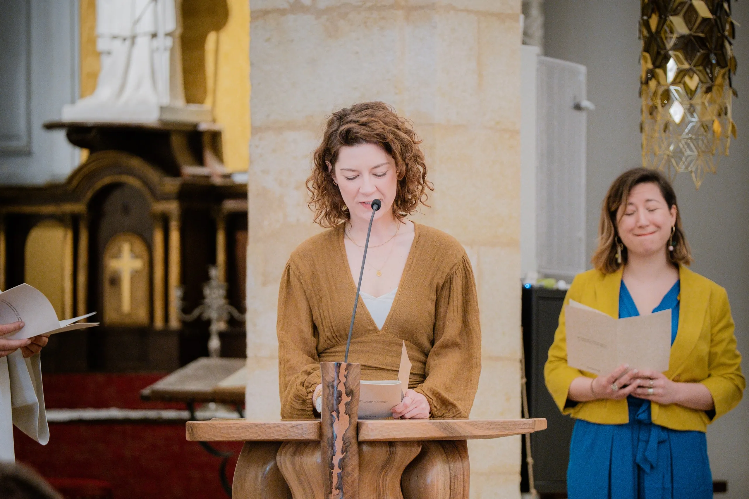 La mère lit un texte au micro, une femme en veste jaune à côté d'elle
