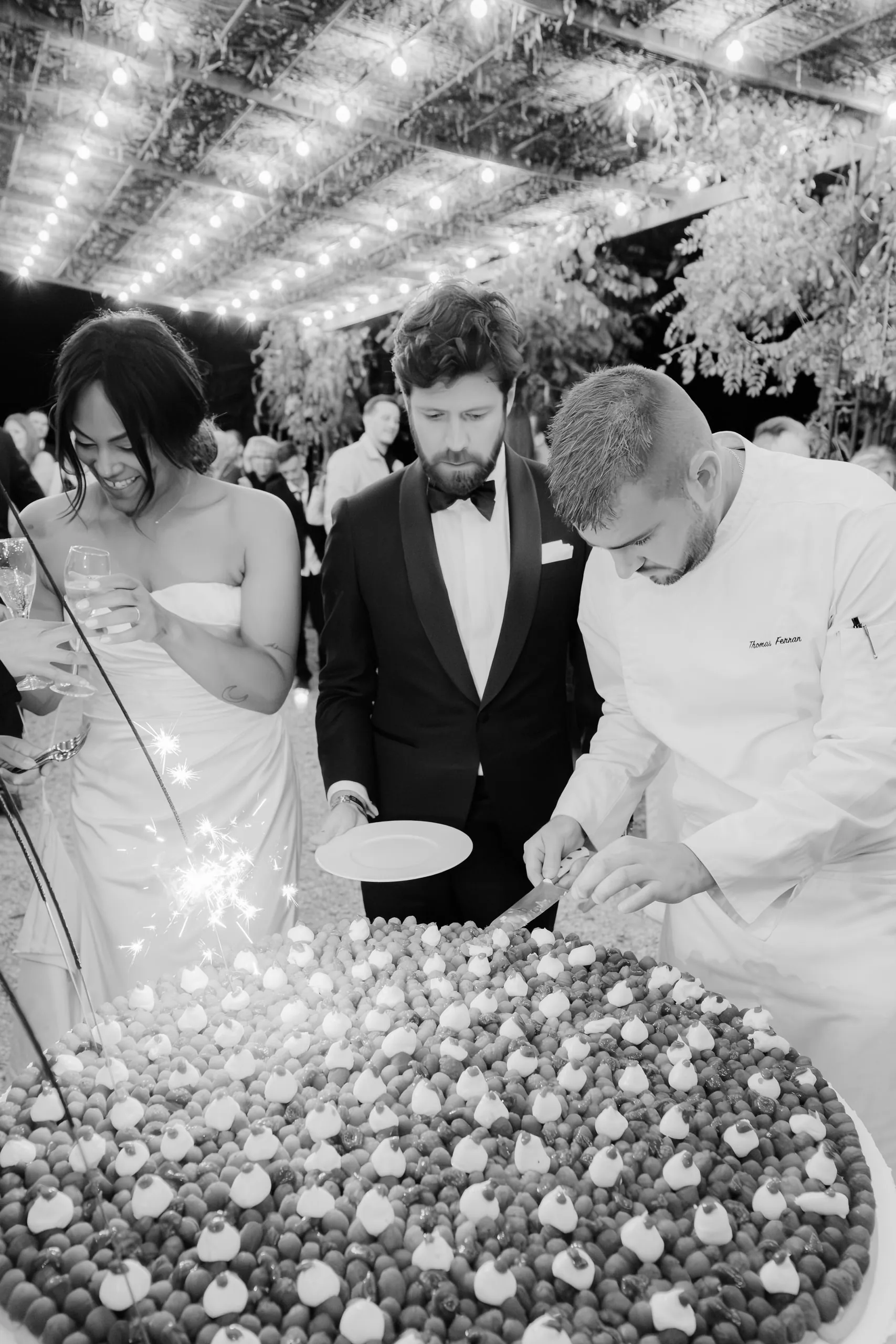 Les mariés et le chef autour de la pièce montée, en noir et blanc