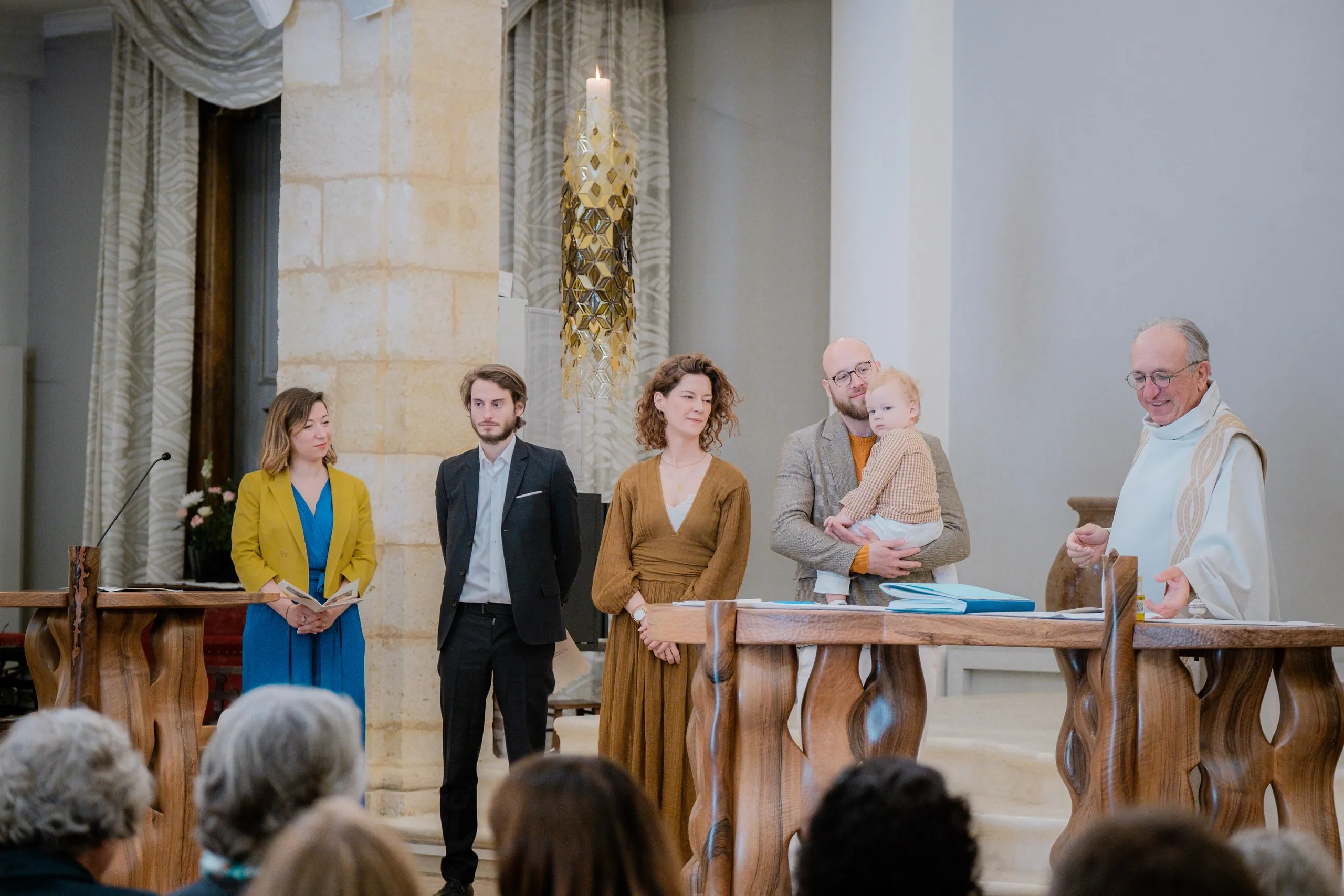 Face à l'assemblée, la famille et deux proches derrière l'autel de la chapelle, le prêtre à leur droite