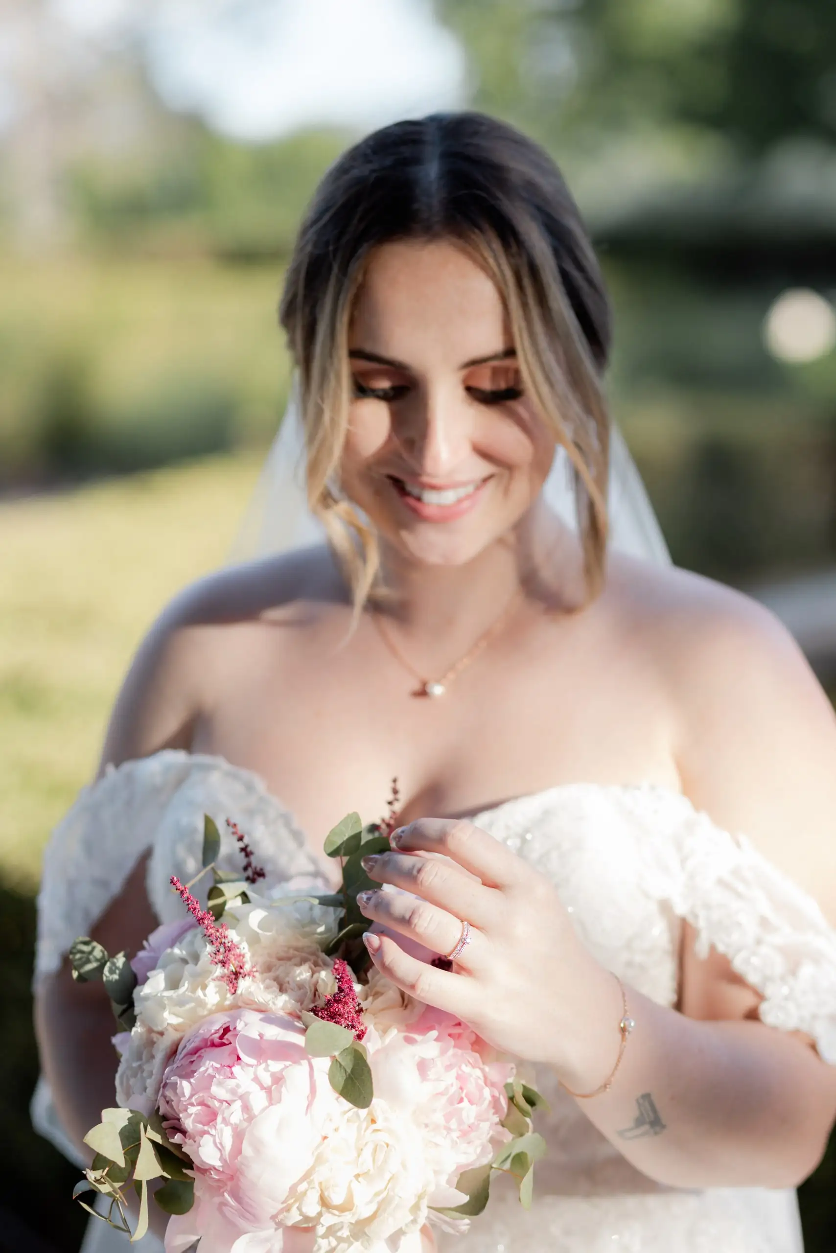 Portrait de la mariée souriante, son bouquet de pivoines dans les bras