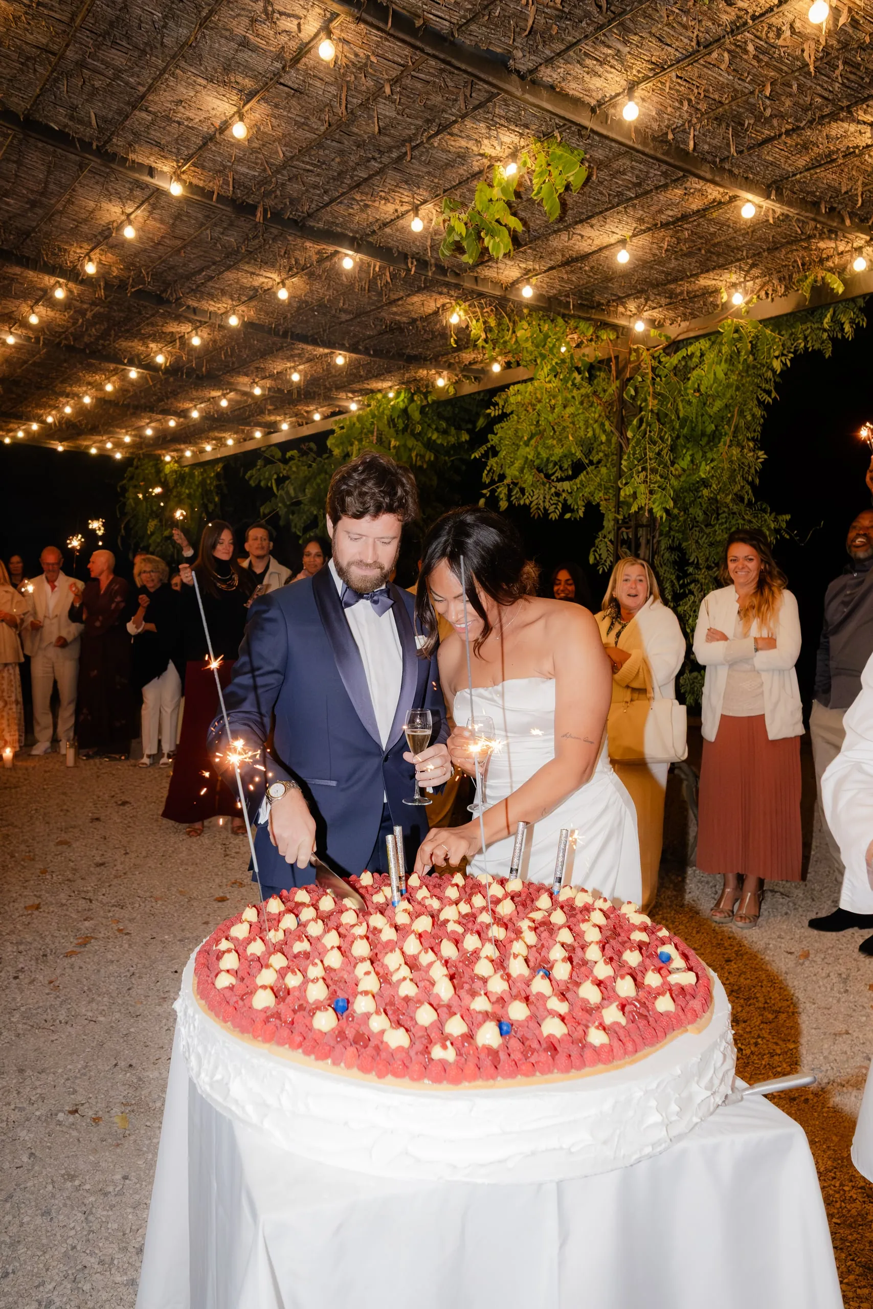 Les mariés découpent leur gâteau aux fraises sous les guirlandes
